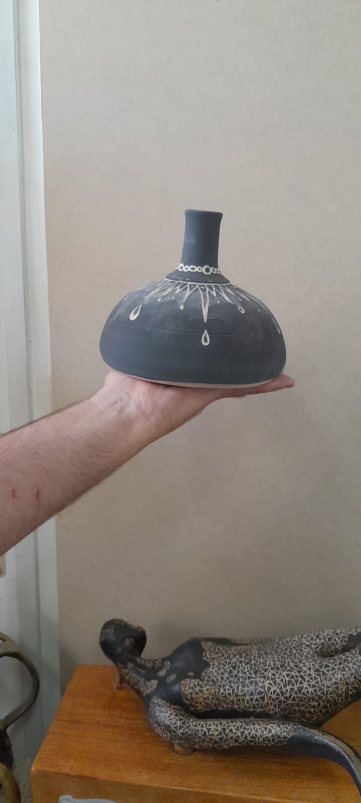 כד קרמיקה שחור עם עיטורי טיפות לבנות מוחזק ביד