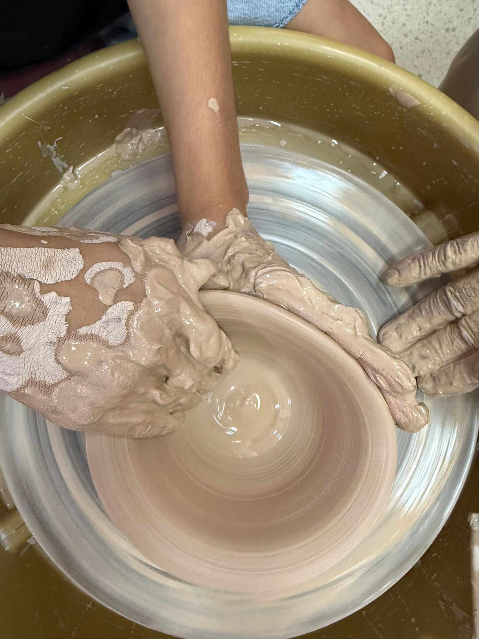 ידיים מכוסות חימר מעצבות כלי קרמיקה על אובניים