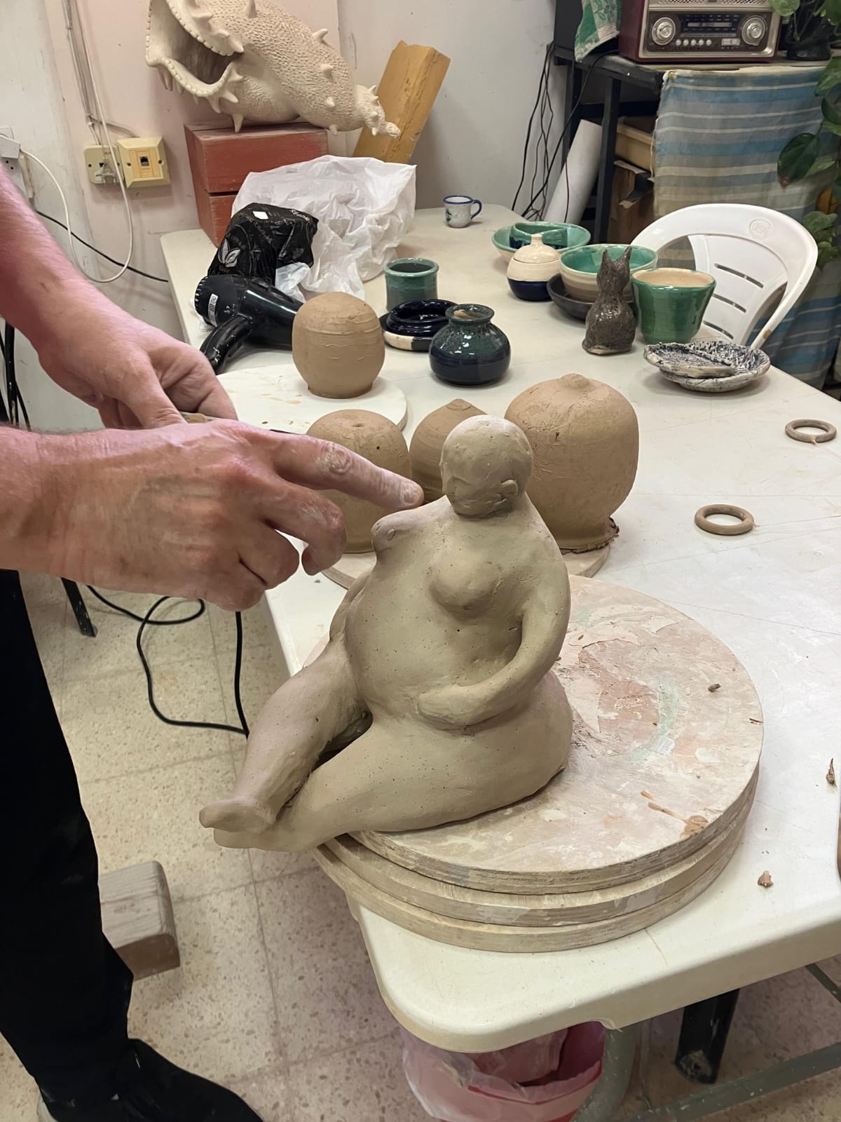 פסלון אישה מחימר בתהליך יצירה בסטודיו